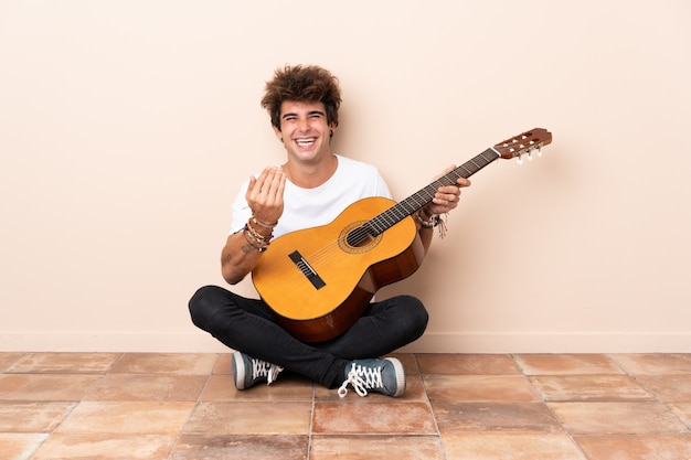 Giovane con la chitarra che si siede sul pavimento