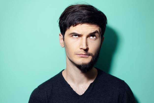 Photo young man with half shaved face looking up on wall of aqua menthe color.