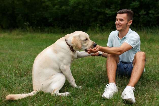 Young man with happy labrador in the park