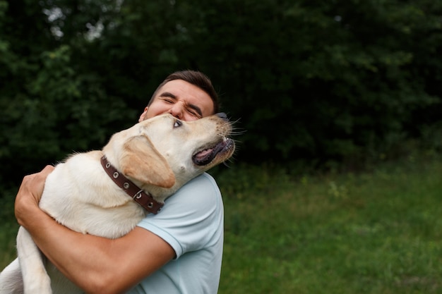 Young man with happy labrador in the park