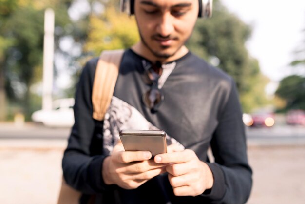 屋外でヘッドフォンと携帯電話を持つ若者