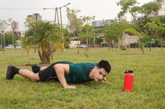 Young man with headphones doing push-ups in the square.