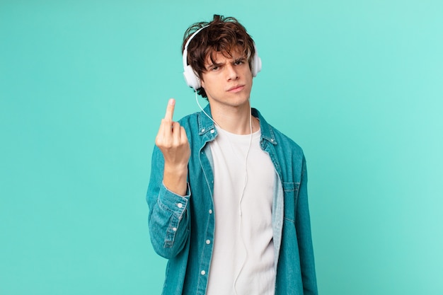 Young man with headphones feeling angry, annoyed, rebellious and aggressive