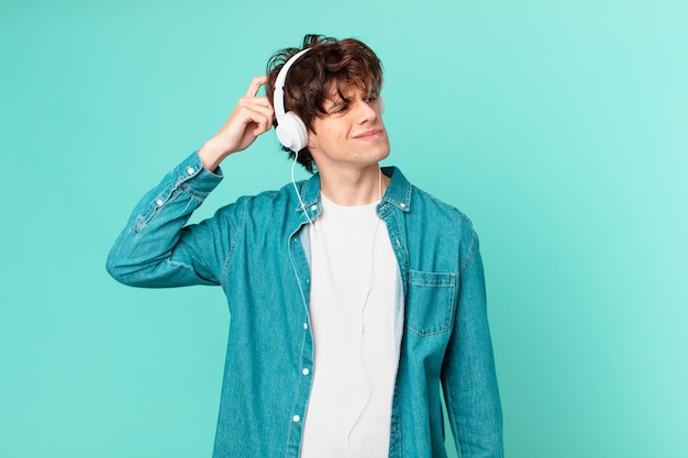 Young man with headphones feeling puzzled and confused, scratching head