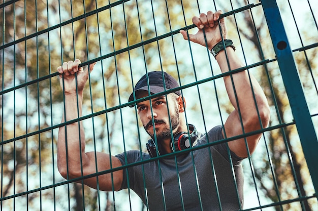 Young man with headphones is resting after training in autumn nature.