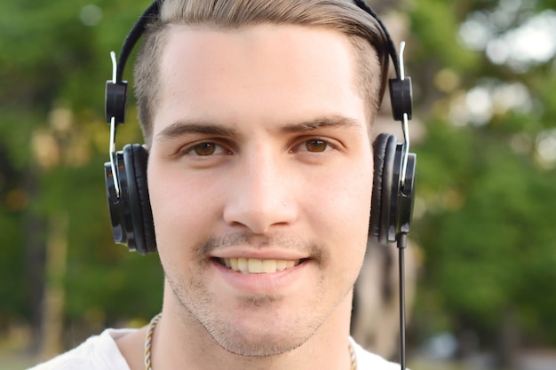 Photo young man with headphones in a park.