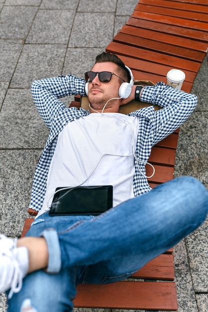 Young man with headphones and tablet outdoors