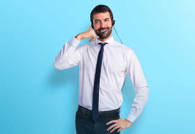 Young man with a headset making phone gesture on colorful background