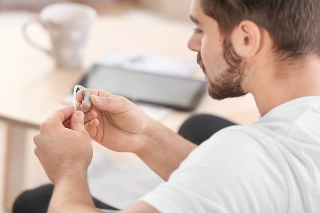 Young man with hearing aid indoors