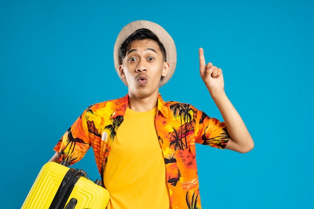 Young man with idea gesture over isolated background in vacation with travel suitcase