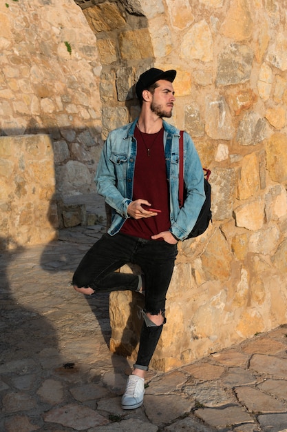 Young man with jacket and cap with castle in background. Lifestyle concept, model.