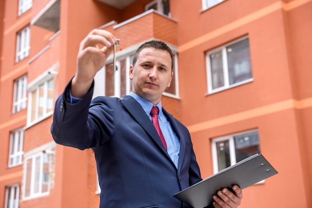 Photo young man with key standing before new building