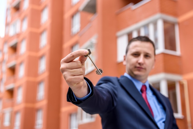 Foto giovane con la chiave in piedi davanti al nuovo edificio