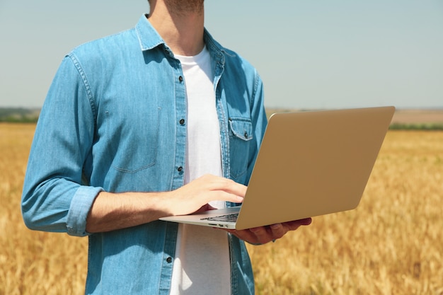 Young man with laptop in barley field