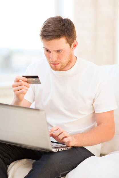 young man with laptop and credit card at home