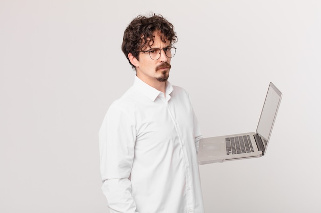 Young man with a laptop feeling sad, upset or angry and looking to the side