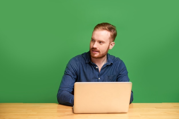 녹색 배경에 고립 된 노트북으로 젊은 남자