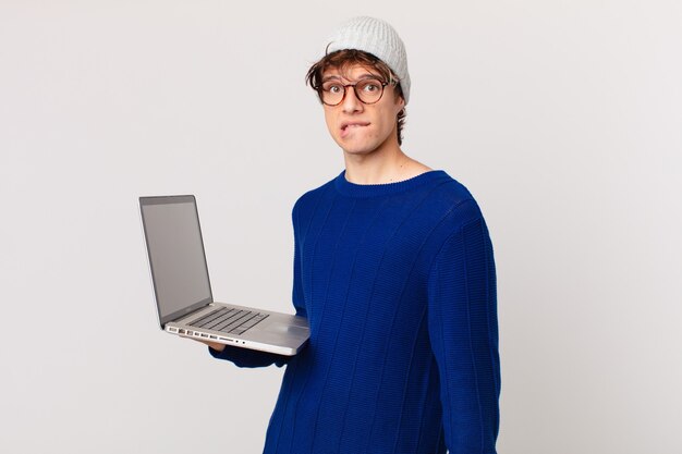 Young man with a laptop looking puzzled and confused