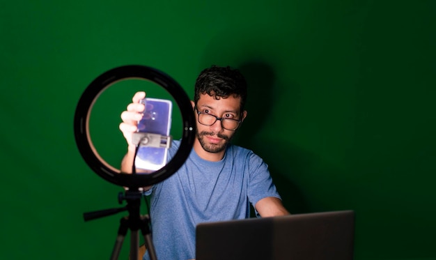 Молодой человек с ноутбуком делает видеоблог Молодой человек создает контент с мобильным телефоном