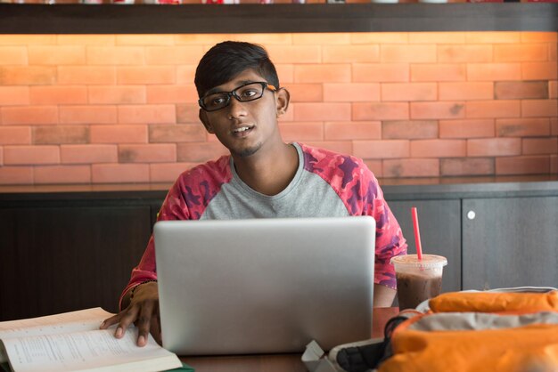 Young man with laptop studying in cafe