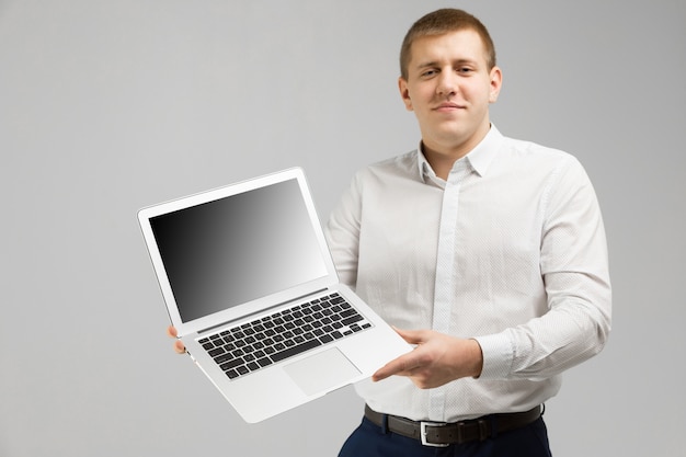 Young man with laptop with an empty screen in his hands is isolated on light 