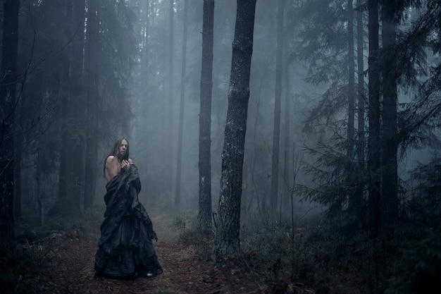  young man with long hair in the dark forest