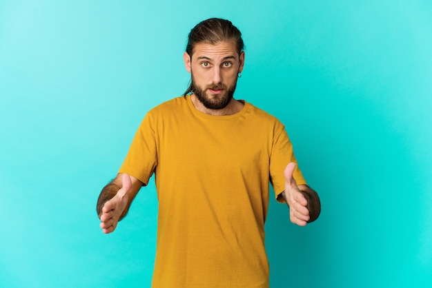 Young man with long hair look holding something with both hands, product presentation.