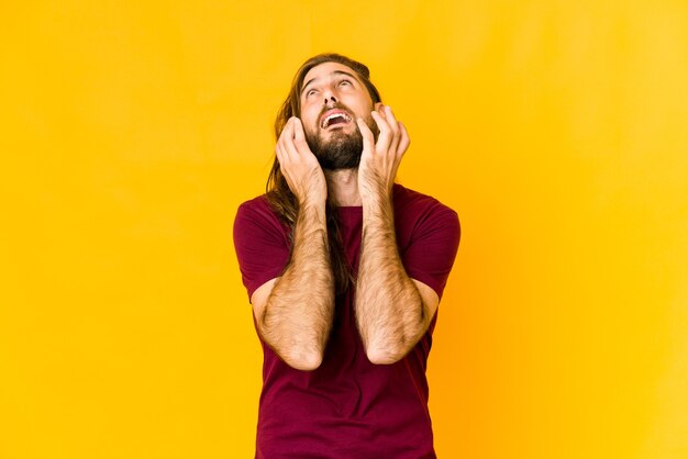 Young man with long hair look whining and crying disconsolately.