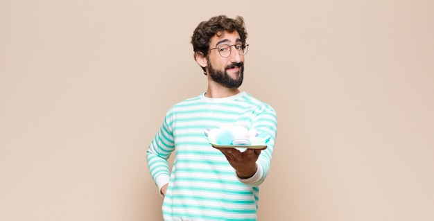 Young man with macaroons on wall