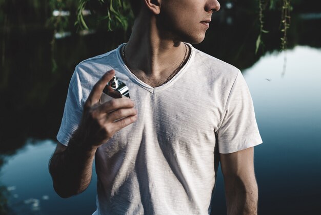 Young man with male perfume in nature