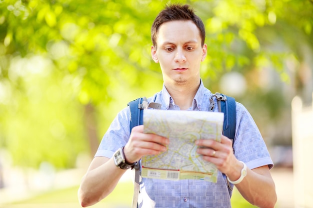 屋外の地図を持つ若い男