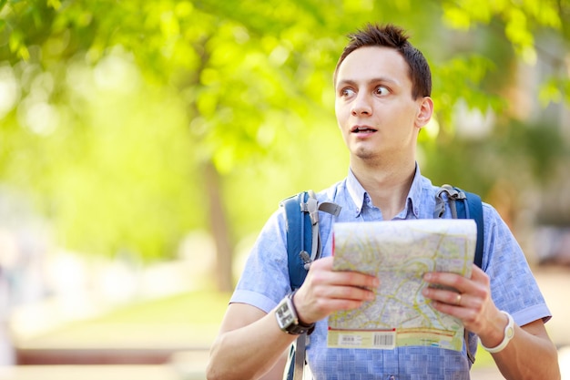 屋外の地図を持つ若い男