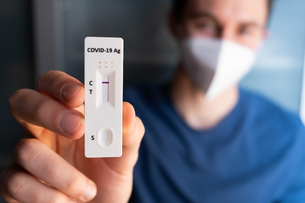 Young man with mask holding a negative self home test Covid19 rapid test Negative result