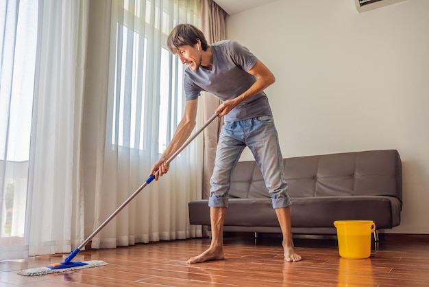 Photo young man with mop cleaning floor at home