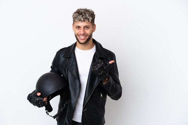 Young man with a motorcycle helmet isolated on white background pointing to the side to present a product