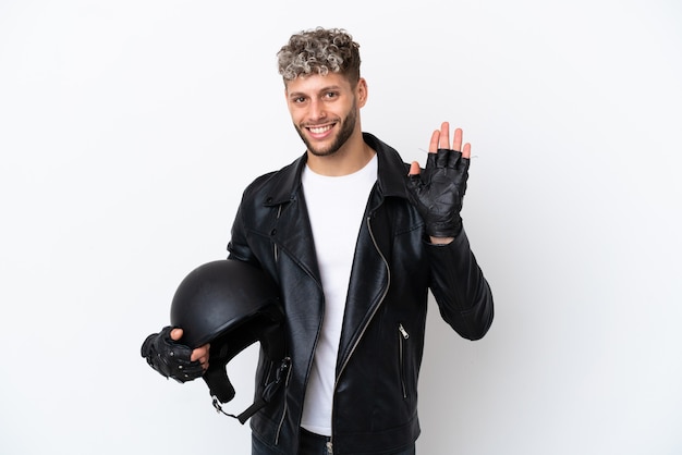 Young man with a motorcycle helmet isolated on white background saluting with hand with happy expression