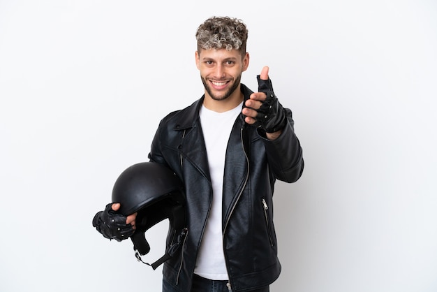 Giovane con un casco da motociclista isolato su sfondo bianco che stringe la mano per aver chiuso un buon affare