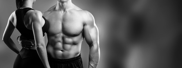 Female hands touching body of sporty young man on dark background Stock  Photo