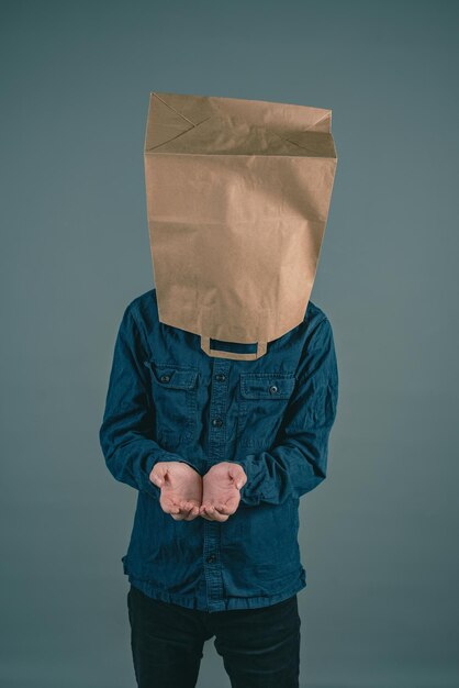 Photo young man with paper bag on his head, open hands for begging, finacial crisis, poverty