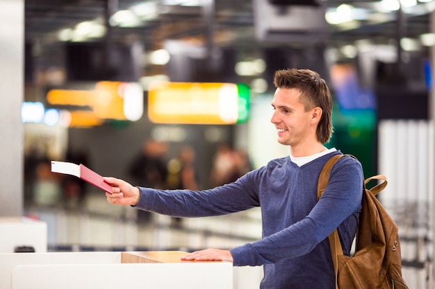 Photo young man with passports and boarding tickets at the front desk in airport