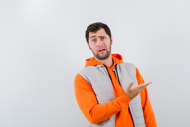 Young man with a perplexed look on his face showing the right with his hands on white background