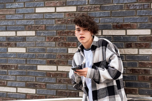 young man with a phone against a brick wall