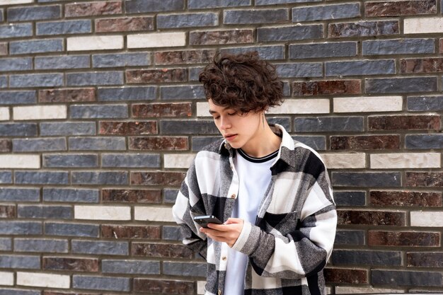 Young man with a phone on the urban background of brick wall