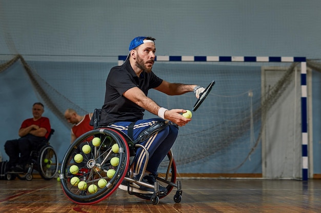 Foto giovane con una disabilità fisica che gioca a tennis su sedia a rotelle sul campo da tennis il giocatore di tennis colpisce la palla durante una partita