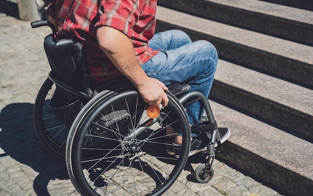 Young man with a physical disability who uses wheelchair in front of the stairs