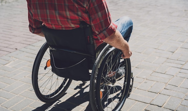 Young man with a physical disability who uses wheelchair walk\
at the street