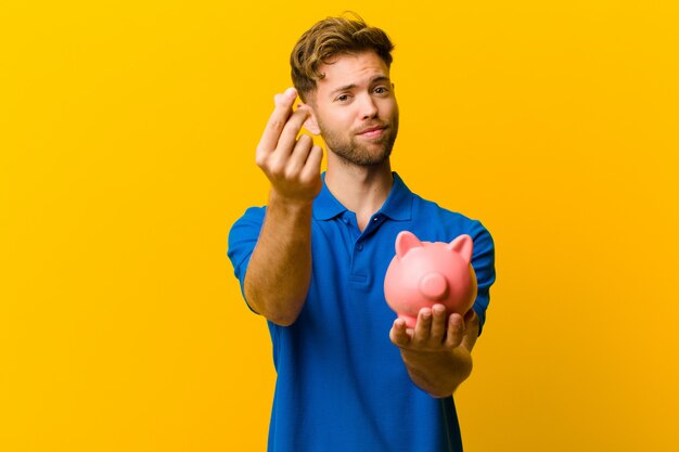 Young man with a piggy bank orange