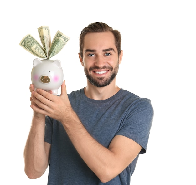 Young man with piggy bank on white