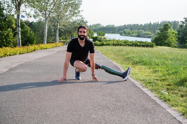 Young man with prosthetic leg exercising in the park outdoors