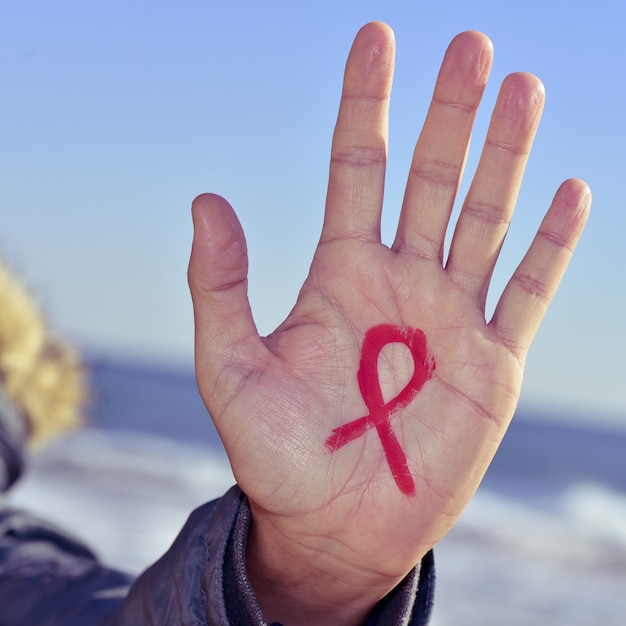 Young man with a red ribbon for the fight against AIDS in his hand